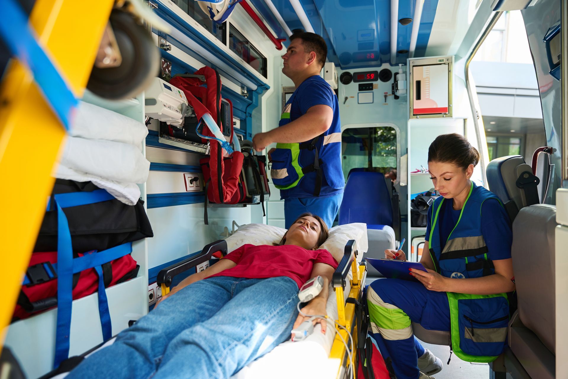 Des ambulanciers soignent une patiente sur une civière à l'intérieur d'une ambulance.