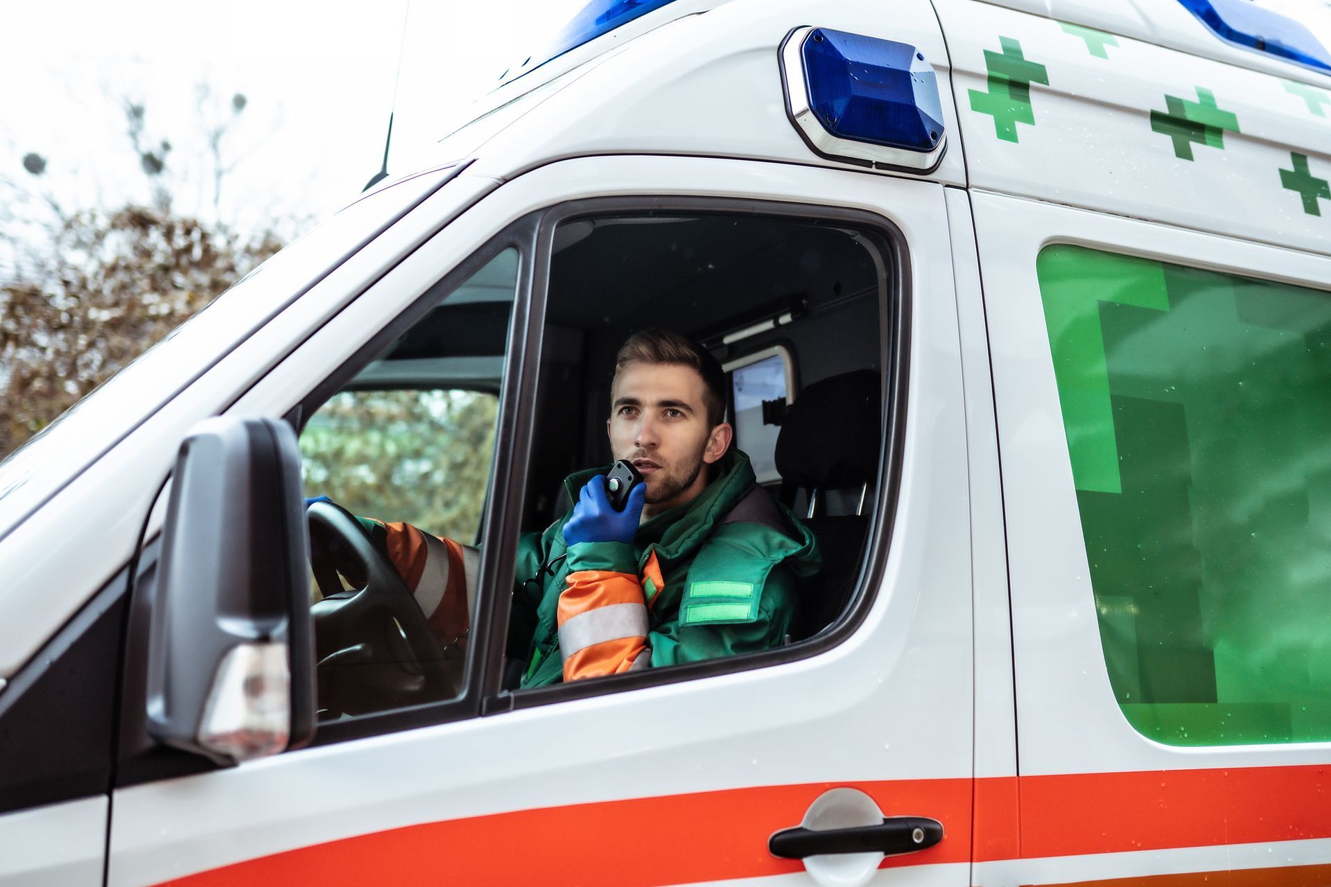 Un ambulancier dans une ambulance blanche, verte et rouge, parlant dans une radio.
