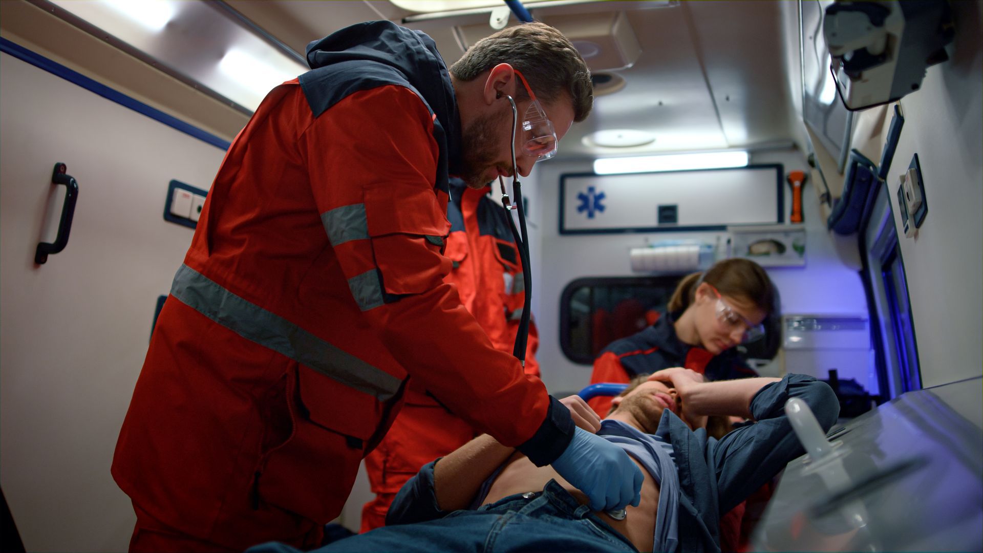 Des ambulanciers prennent les constantre d'un patient dans une ambulance.