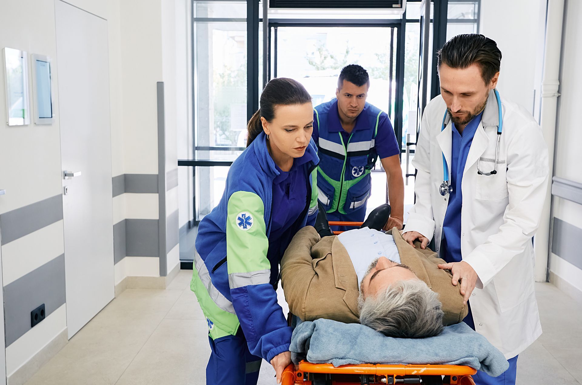 Des ambulanciers et un médecin transportent en urgence un homme blessé sur une civière dans un couloir d'hôpital.