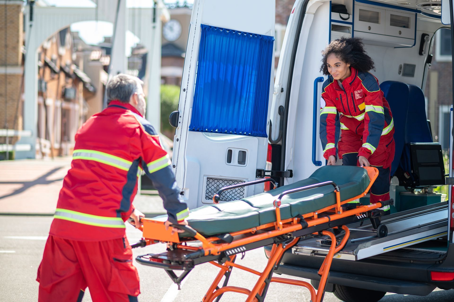 Deux ambulanciers chargent une civière dans une ambulance, l'un à l'intérieur et l'autre à l'extérieur.