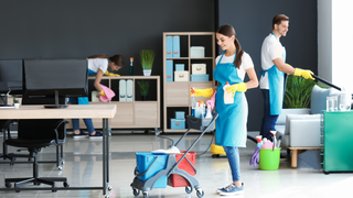 Persona en la plataforma elevadora limpiando el exterior del edificio con una manguera de alta presión.