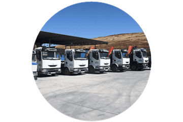 Una fila de camiones están estacionados bajo un toldo en un estacionamiento.