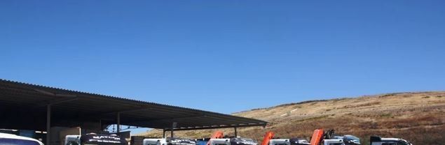 Una fila de coches están aparcados bajo un toldo en una gasolinera.