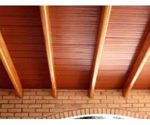 Un techo de madera con vigas en una pared de ladrillo.