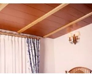 Un dormitorio con techo de madera y cortinas.