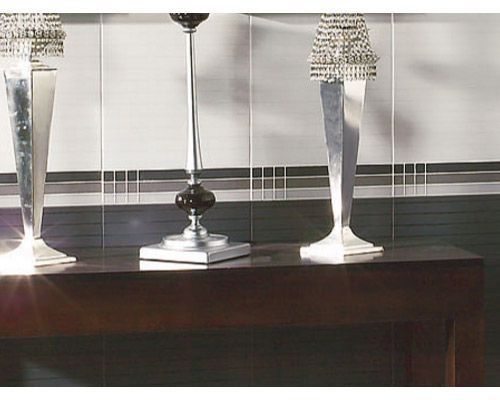 Dos lámparas están sobre una mesa frente a una pared de azulejos.