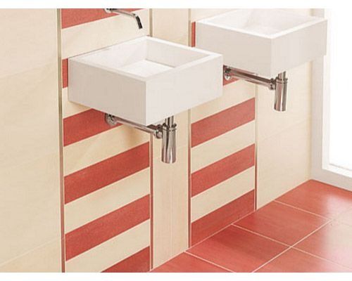 Dos lavabos blancos en un baño con rayas rojas y blancas en la pared.