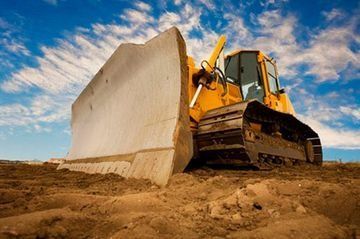 Una excavadora está moviendo tierra en un sitio de construcción.