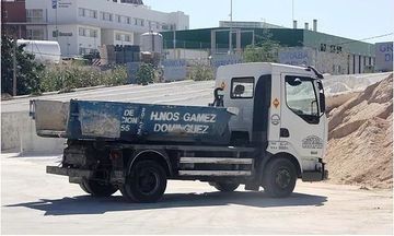 Un camión volquete está estacionado al costado de la carretera frente a un edificio.