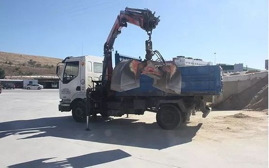 Un camión con una grúa acoplada está estacionado en un estacionamiento.