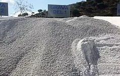 Hay un montón de grava al costado de una carretera al lado de un cartel.