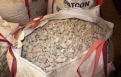 Una bolsa llena de piedras está encima de una pila de piedras.