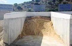 Un gran montón de tierra se encuentra al lado de un muro de hormigón.