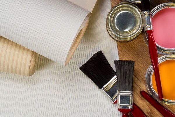 Un montón de pinceles y latas de pintura sobre una mesa de madera.