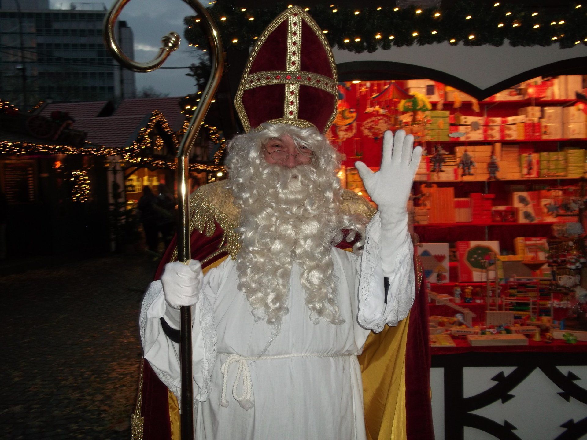 Nikolaus Winkt lächelnd auf dem Weihnachtsmarkt