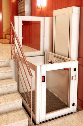 Un ascensor blanco está situado al lado de un conjunto de escaleras.