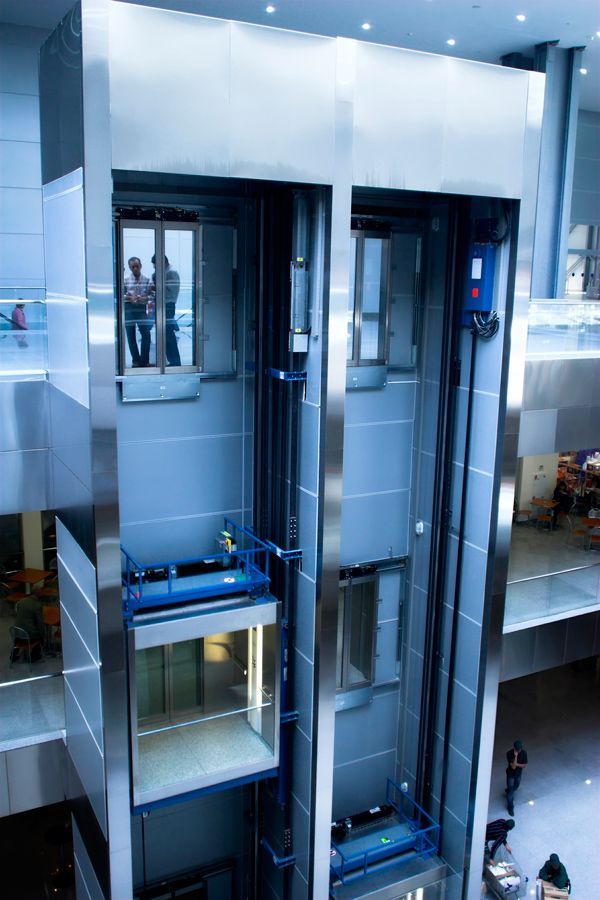 Un gran ascensor en un edificio con gente de pie en él.