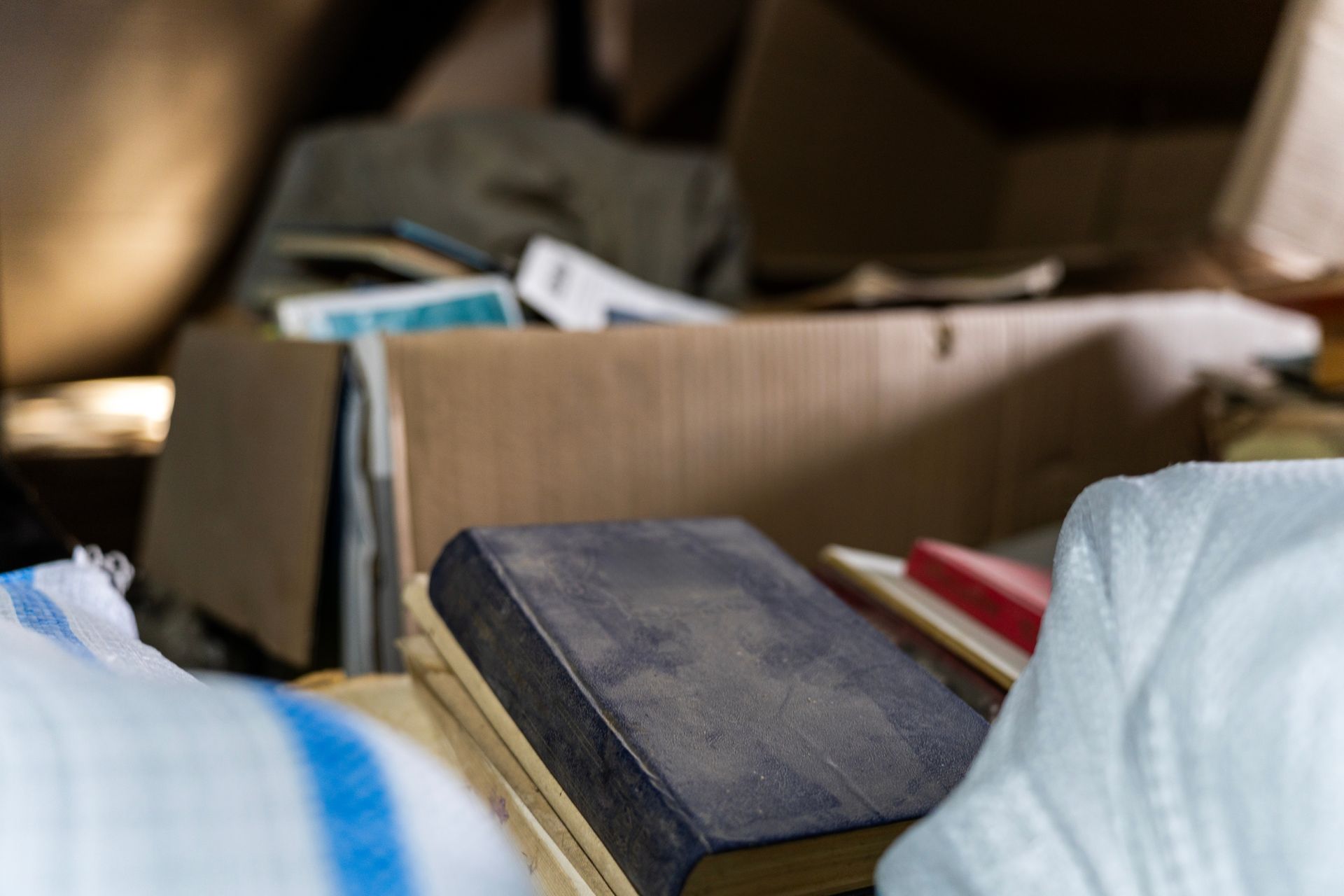 Des livres et des papiers dans une boîte en carton ouverte, avec un livre noir au premier plan.