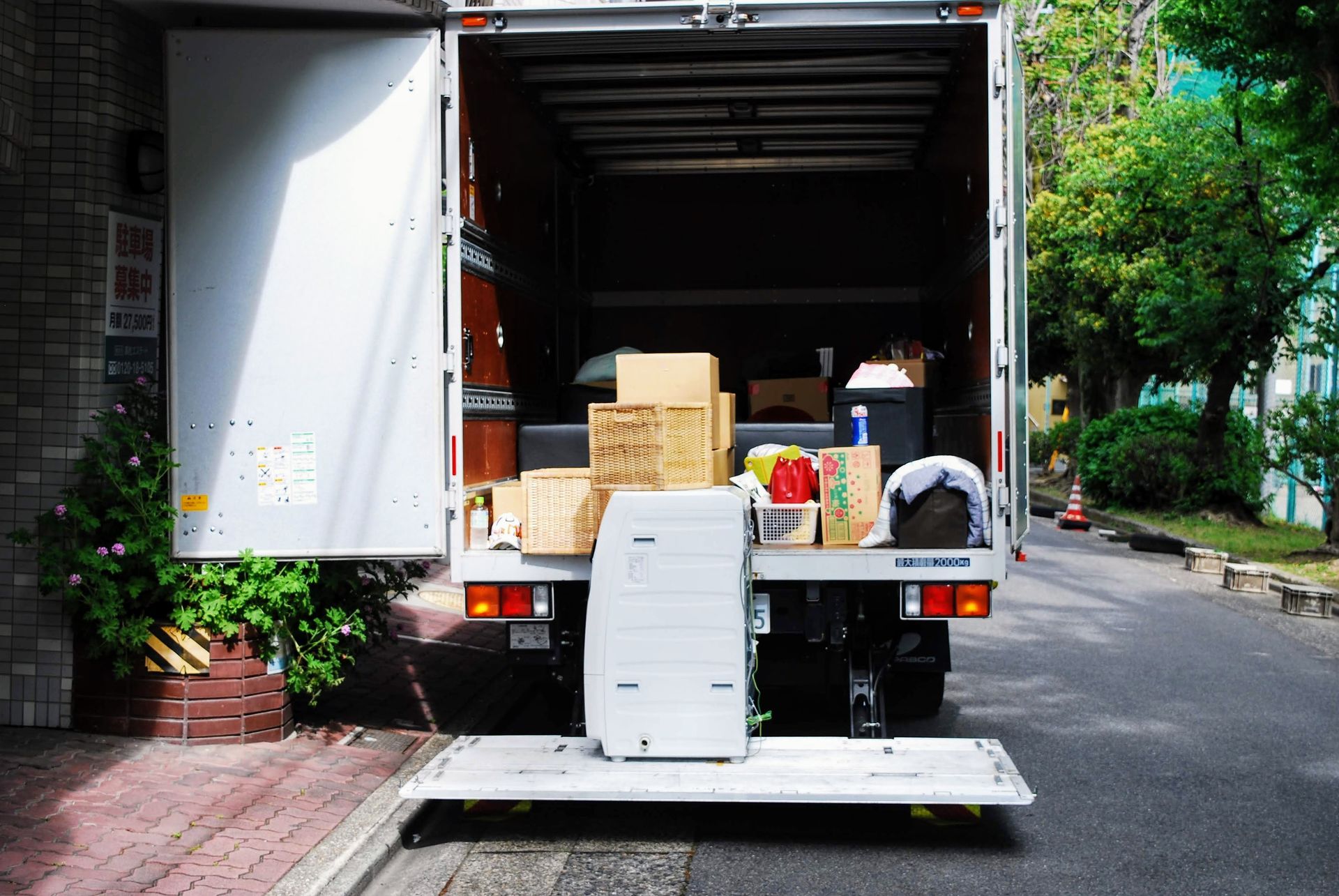 Camion de déménagement avec rampe de chargement abaissée, cartons et articles ménagers à l'intérieur.
