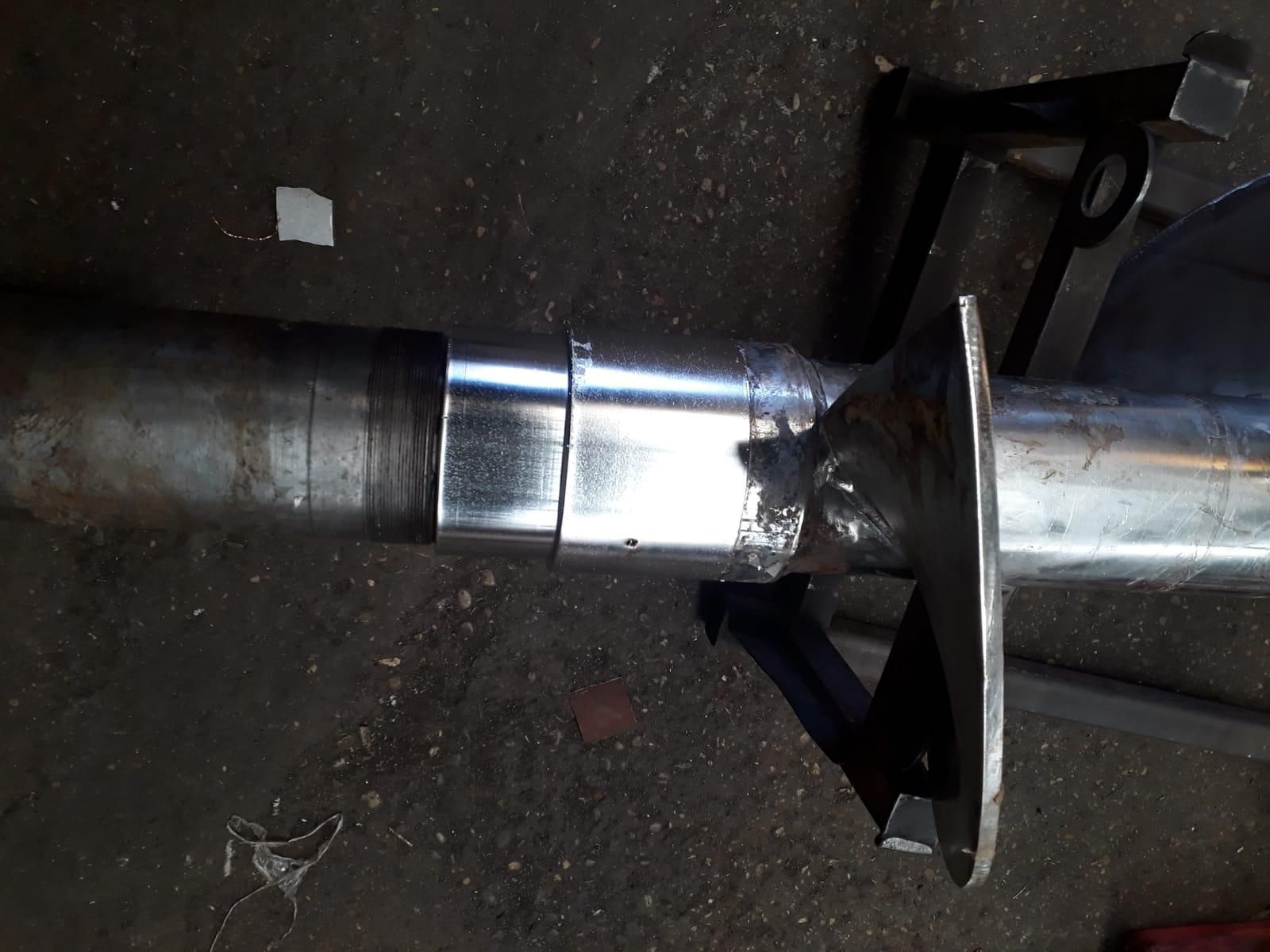 Un primer plano de una tubería de metal apoyada en el suelo.