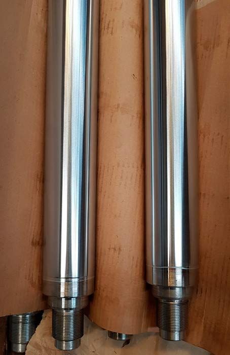 Tres tubos de metal están colocados uno encima del otro sobre una mesa de madera.