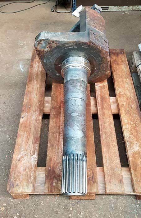 Un eje de metal se encuentra encima de una paleta de madera.