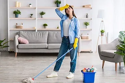 Una mujer está limpiando el suelo de una sala de estar con un trapeador.