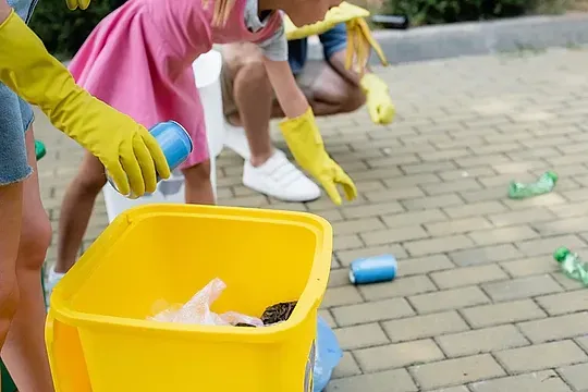 Un grupo de personas con guantes amarillos están limpiando la acera.