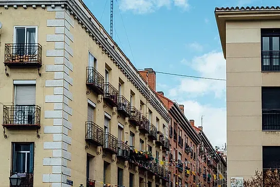 Una hilera de edificios con balcones y un cielo azul al fondo.
