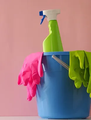 Un cubo azul lleno de productos de limpieza sobre una mesa.