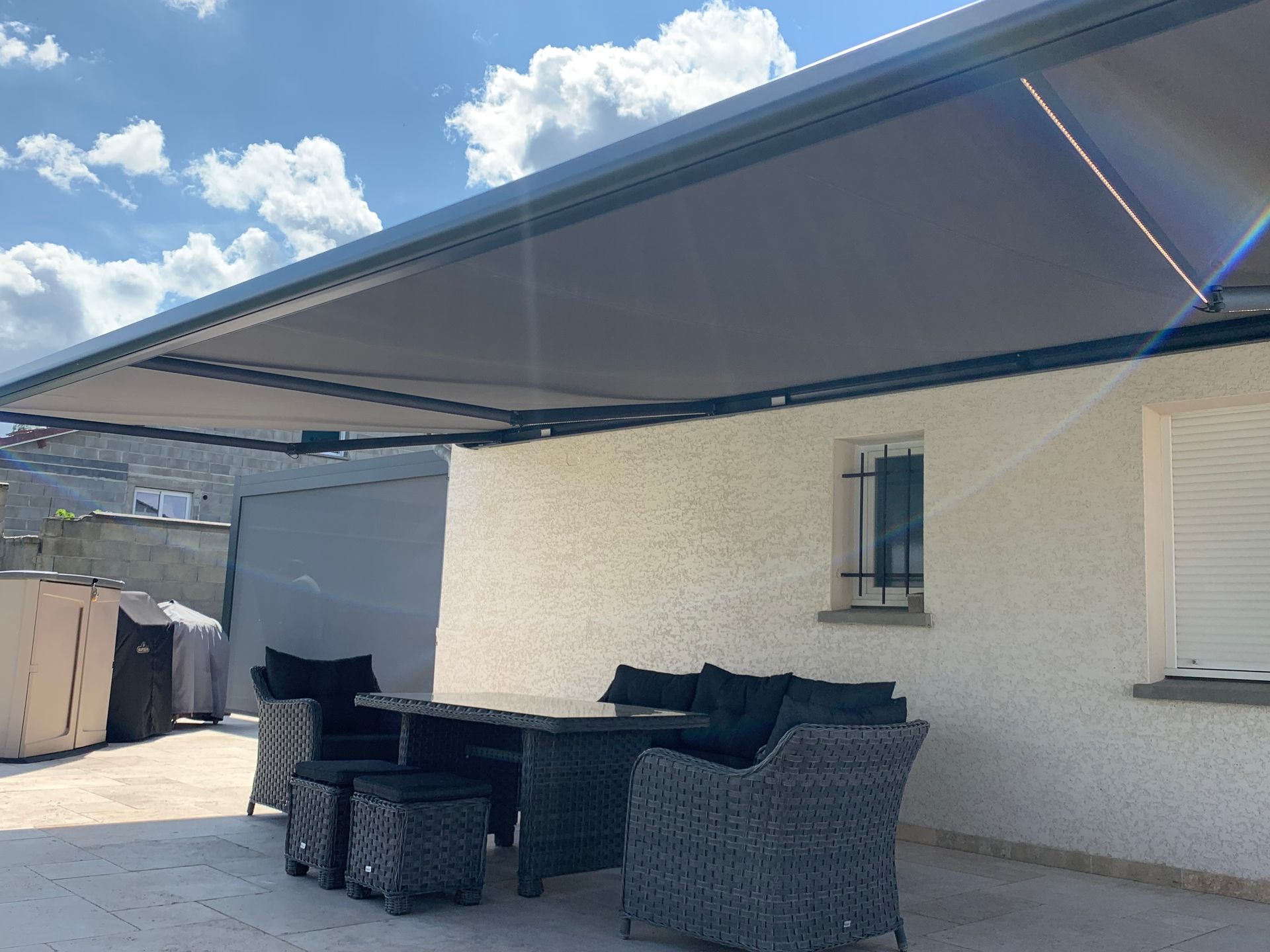 Meubles de jardin couverts par un store banne ouvert