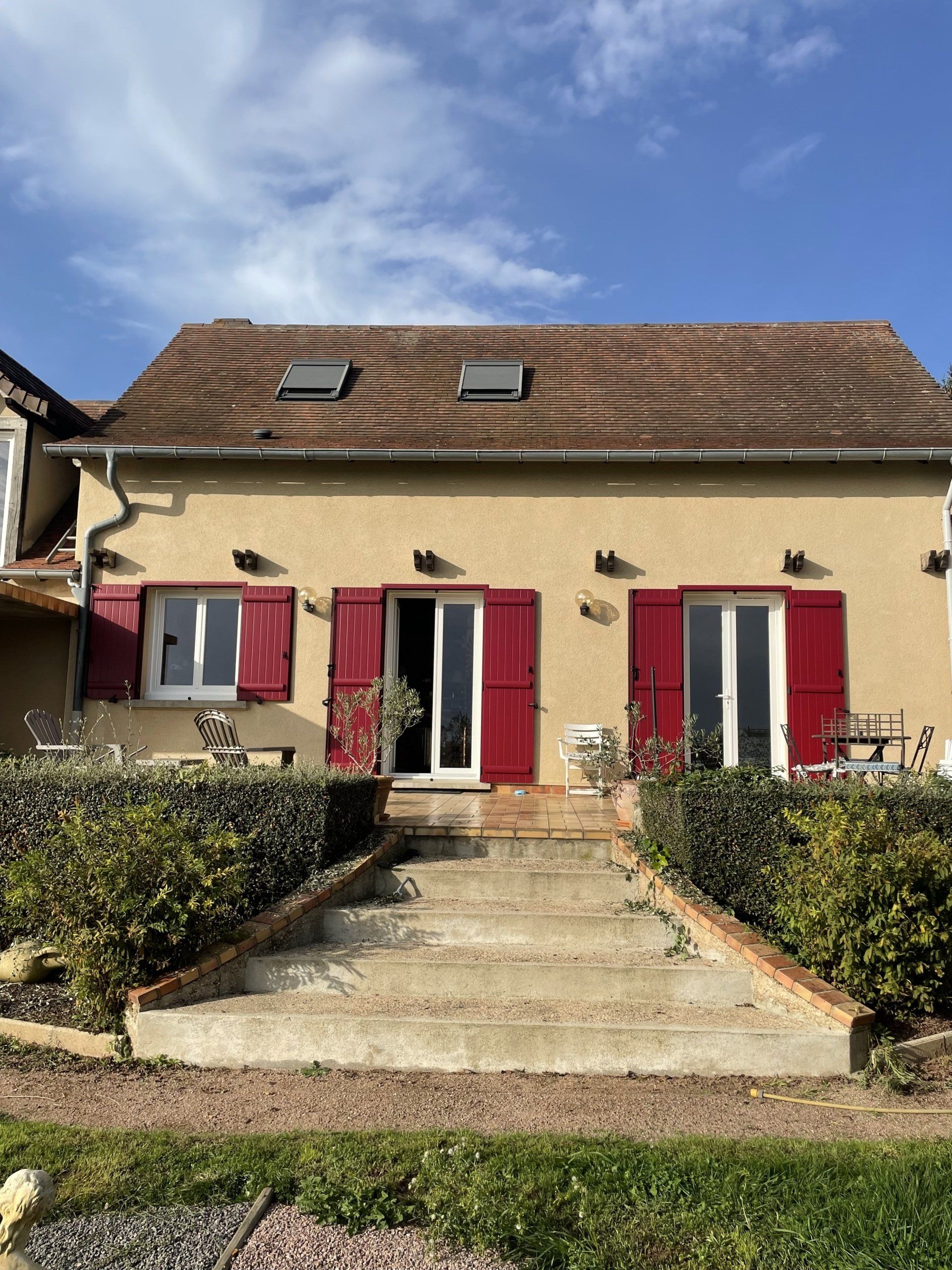 Vue sur la façade d'une maison avec des volets battants rouges