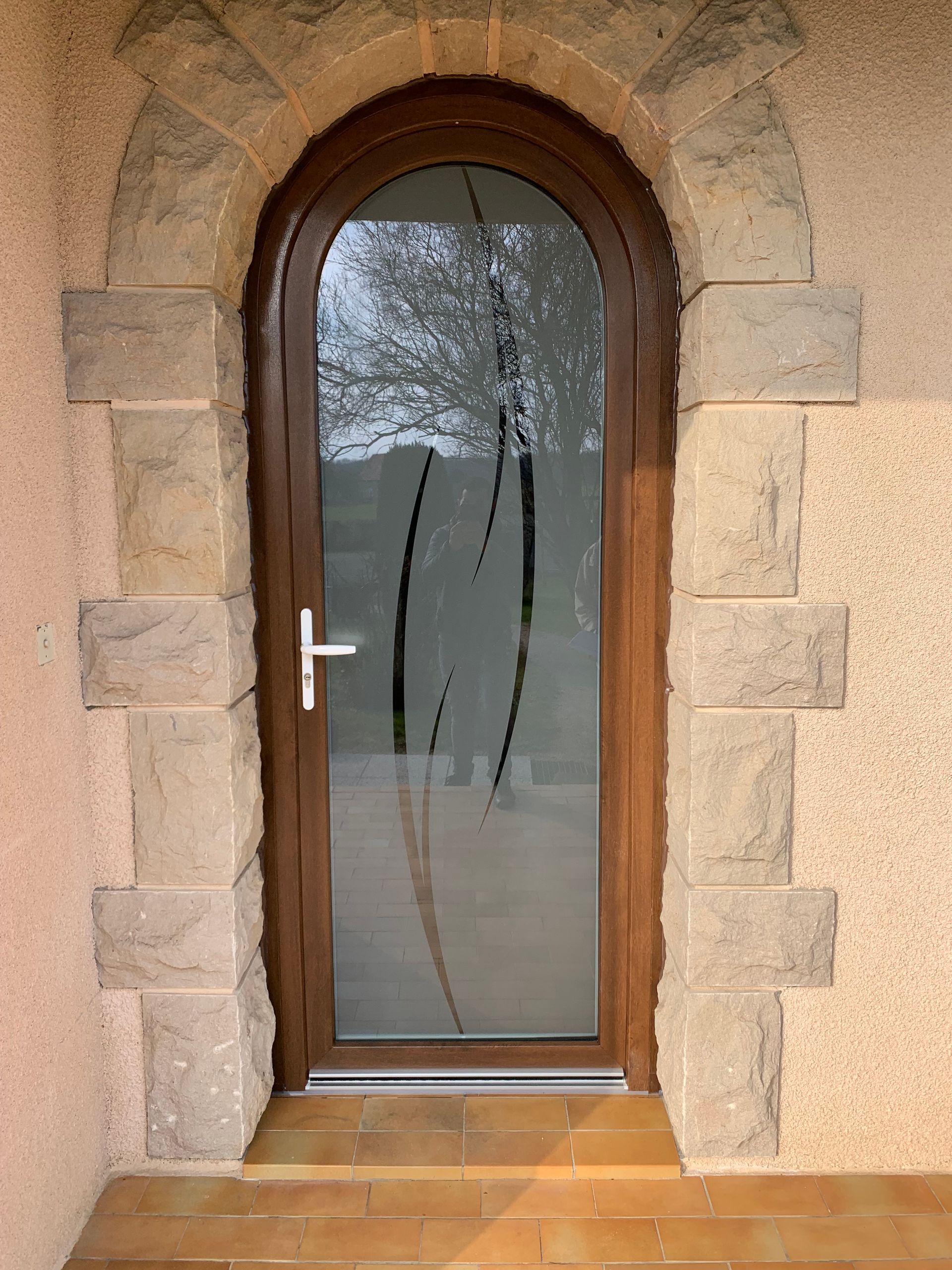 Vue sur une porte d'entrée avec une vitre à forme dessinée