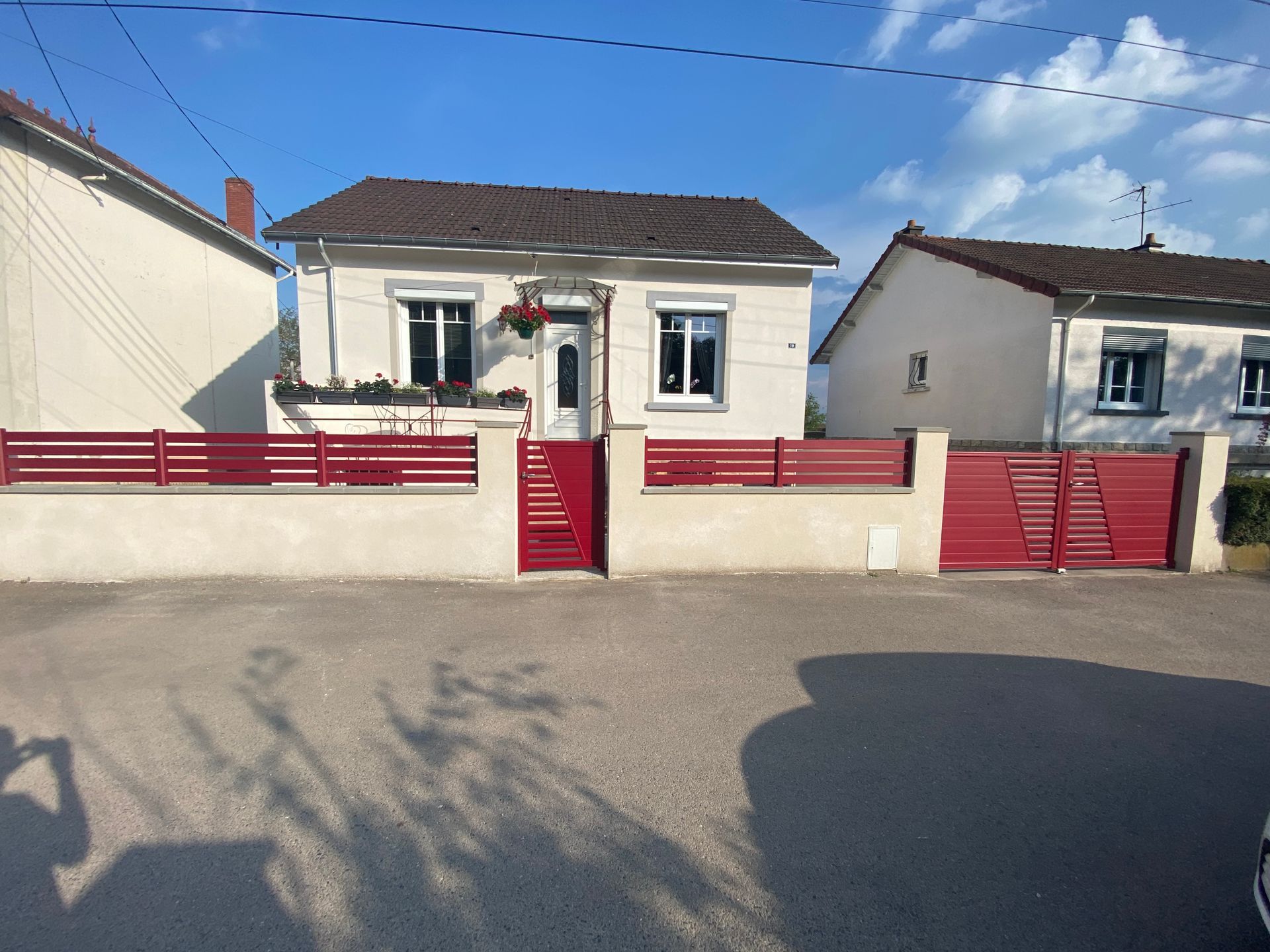 Vue sur la clôture d'une maison avec un portillon rouge