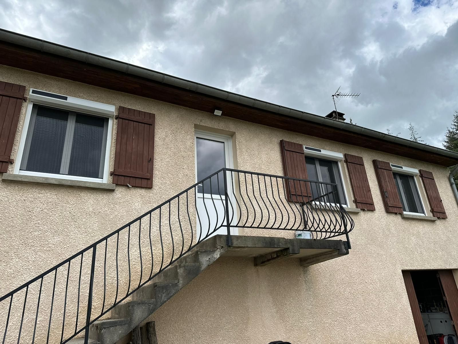 Maison à volets battants marron avec un escalier