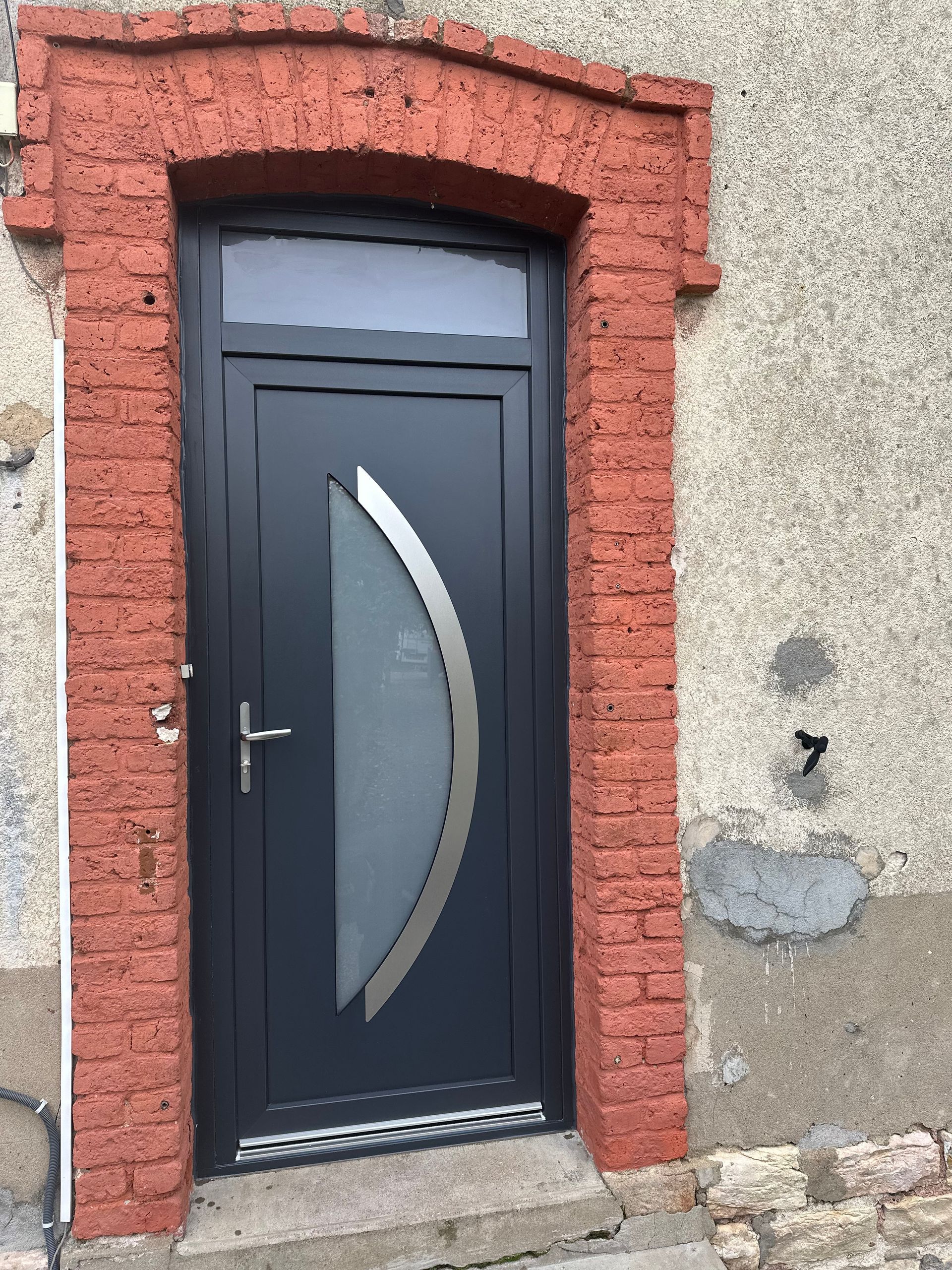 Porte d'entrée gris foncé avec cadre de porte en brique