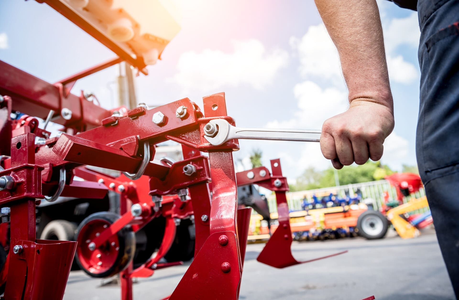 Una persona sujeta una palanca metálica en una máquina agrícola roja al aire libre en un evento.