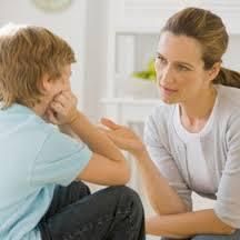 Mujer hablando con un niño sentado en una habitación luminosa