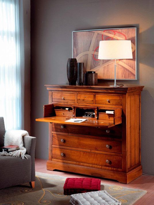 Escritorio de madera con tapa abatible, lámpara, obra de arte y sillón moderno.