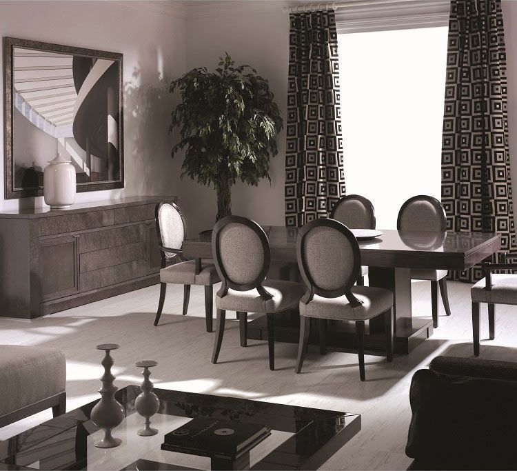 Elegante comedor con mesa, sillas, aparador, espejo, árbol y cortinas estampadas.