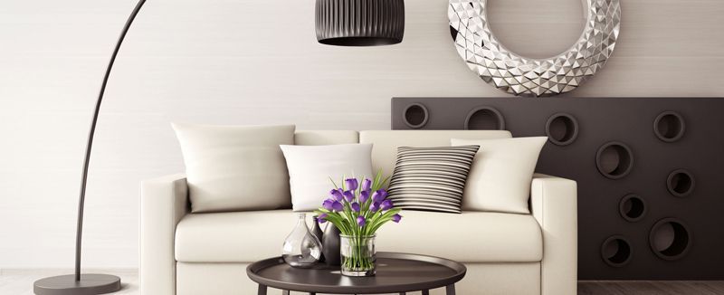 Salón con sofá color crema, lámpara negra y mesa de centro redonda con flores.