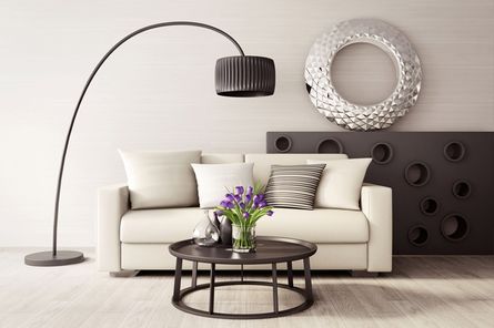 Salón moderno con sofá color crema, lámpara de arco negra, mesa de centro oscura y arte decorativo en la pared.