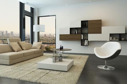 Salón moderno con vistas a la ciudad, sofá beige, silla blanca y estantes flotantes.