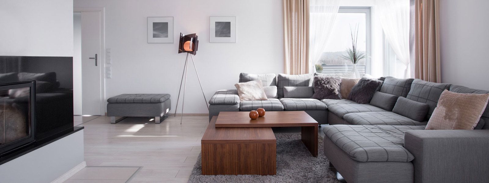 Salón moderno con sofá seccional gris, mesa de centro de madera y chimenea.