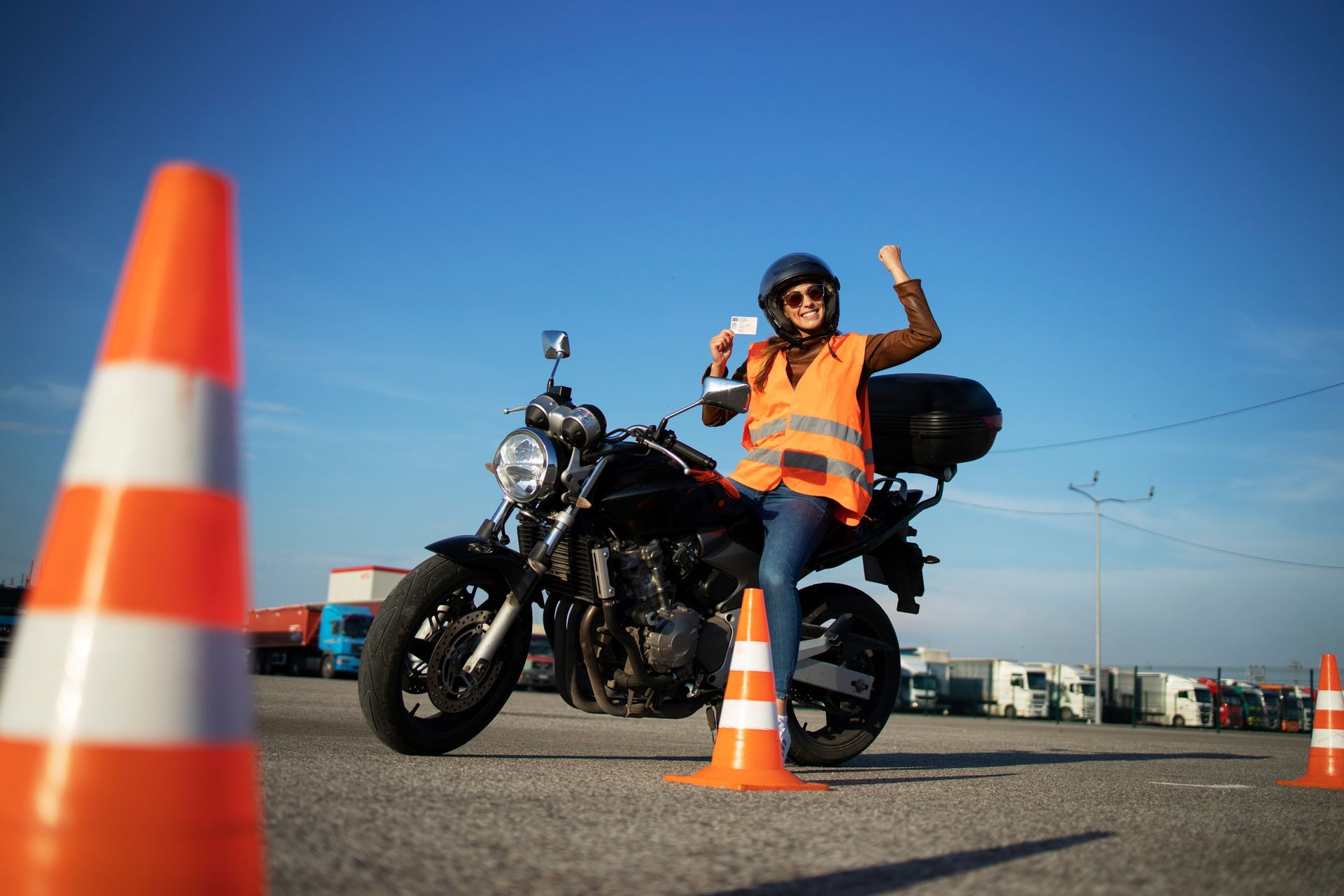 Eine Frau sitzt auf einem Motorrad, umgeben von Verkehrskegeln.