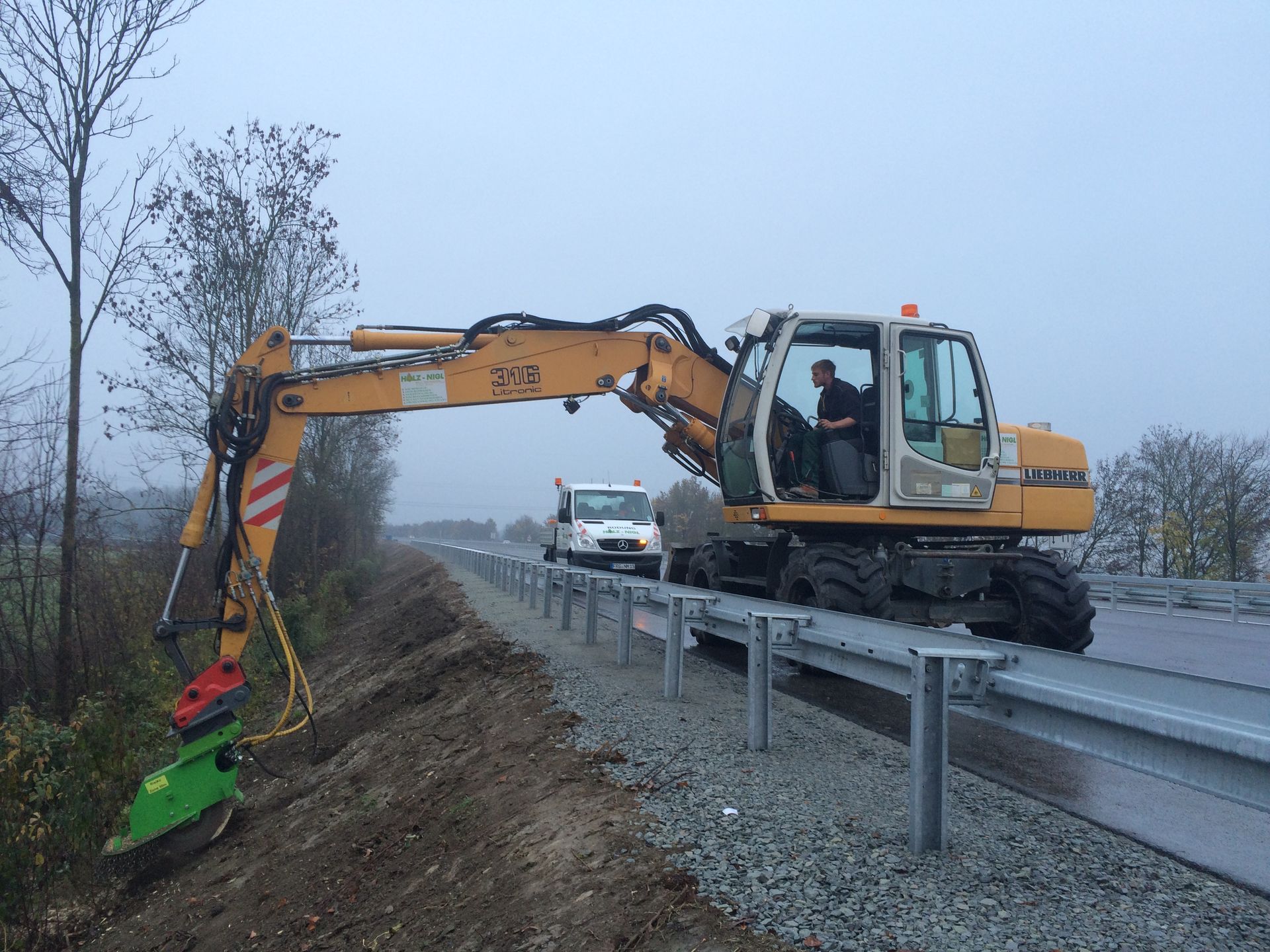 Ein Bagger nimmt Wurzelstockfräßarbeiten am Rand einer Straße vor