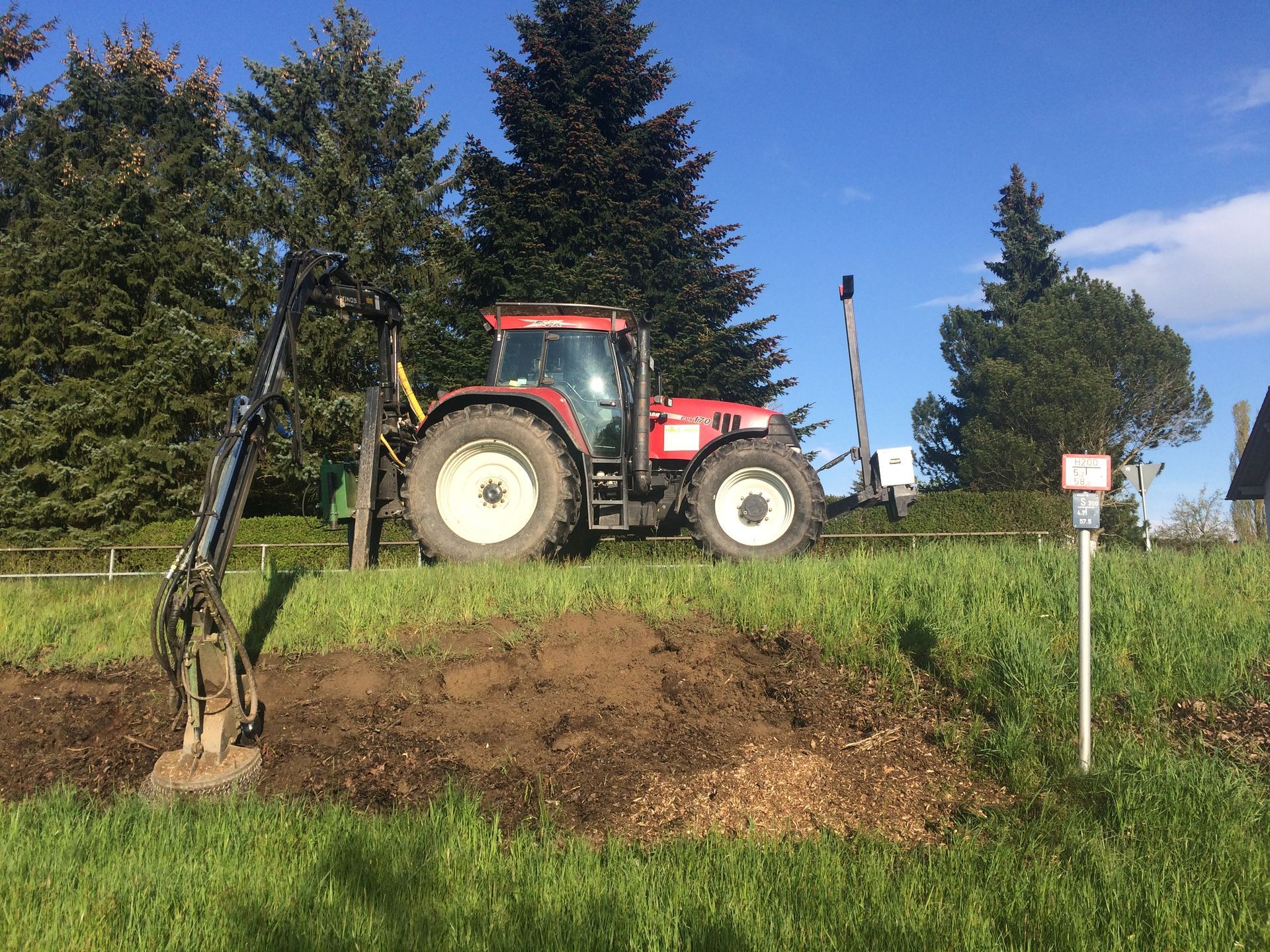 Ein Traktor mit entsprechender Gerätschaft nimmt Wurzelstockfräßarbeiten vor