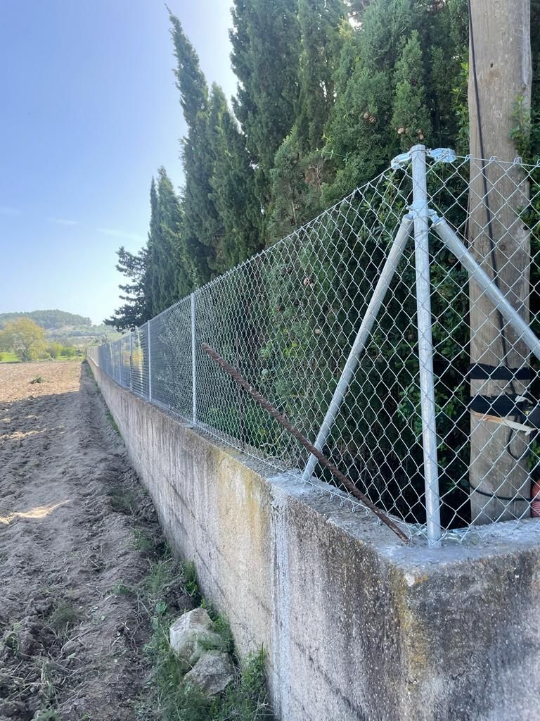 Una valla de alambre rodea un muro de hormigón.