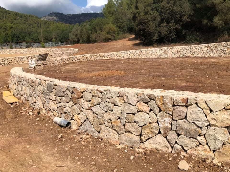 Se está construyendo un muro de piedra en medio de un campo de tierra.